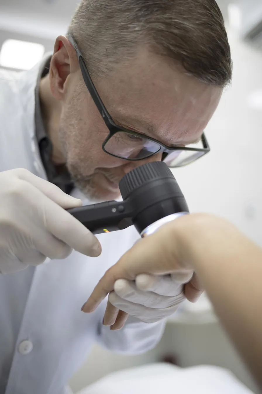 Dr. Joelson Reis Ciacci examinando a pele de um paciente com dermatoscópio, na Dermocentro.